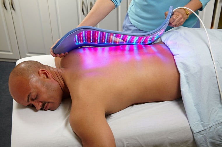 Man laying on table getting cold laser therapy on his back