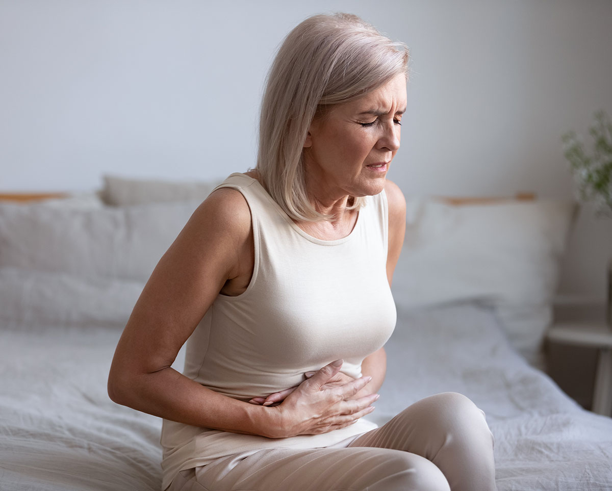 middle aged woman holding her stomach in pain