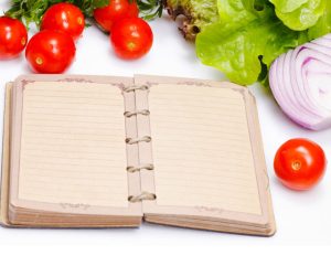 an open journal with vegetables surrounding it 