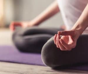 person sitting cross-legged, meditating