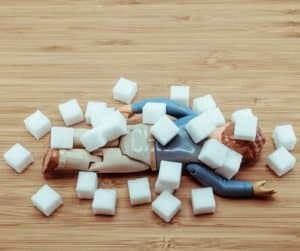 a small figurine being buried by sugar cubes 