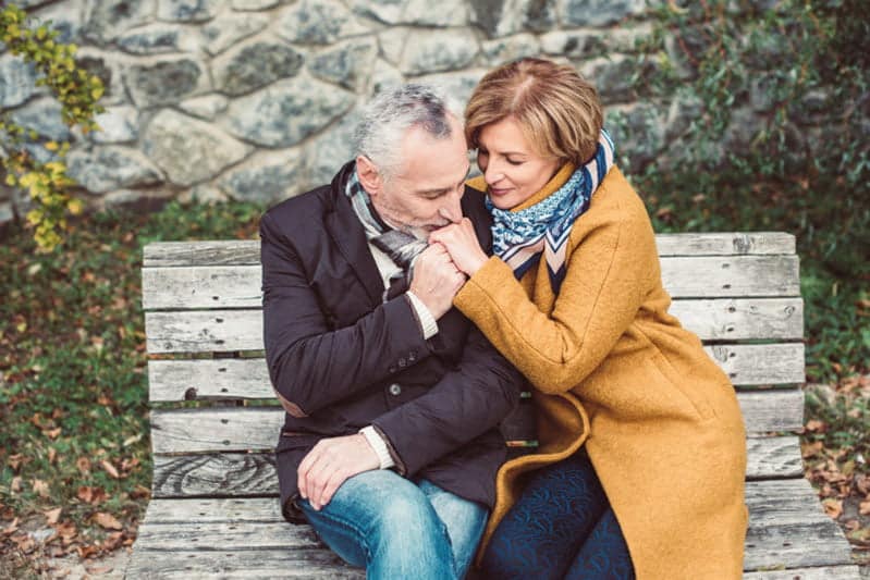 elderly man kissing hand of elderly woman