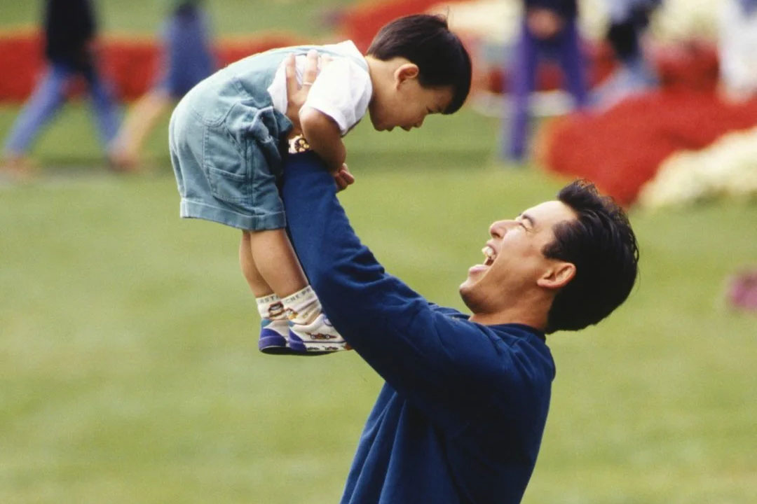 man lifting his toddler son in the air and looking up at him